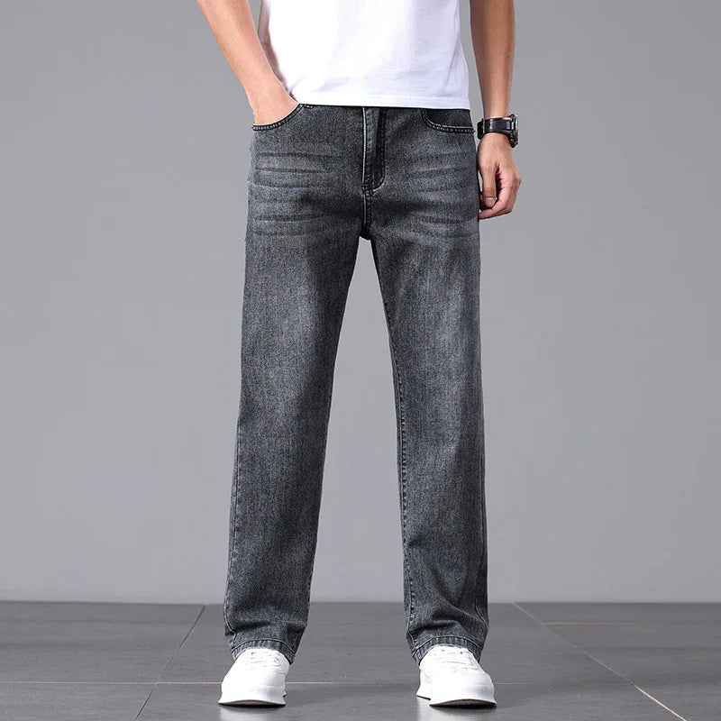 Person wearing gray jeans and white sneakers on a gray background