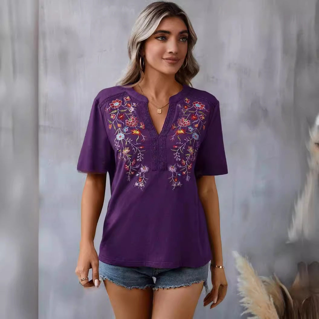 Woman wearing a purple embroidered top with floral designs against a neutral background