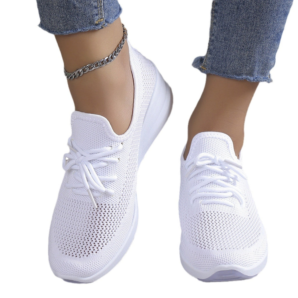 White sneakers worn with blue jeans on a white background