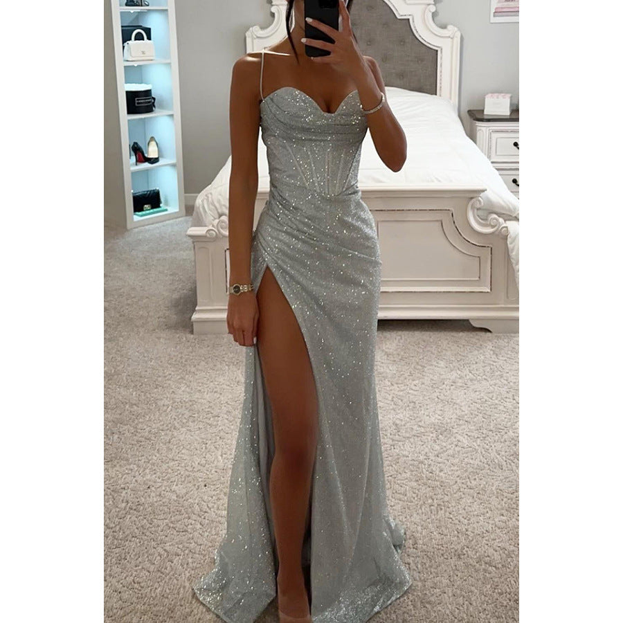 Woman wearing a sparkly silver dress with a high slit in a bedroom setting.
