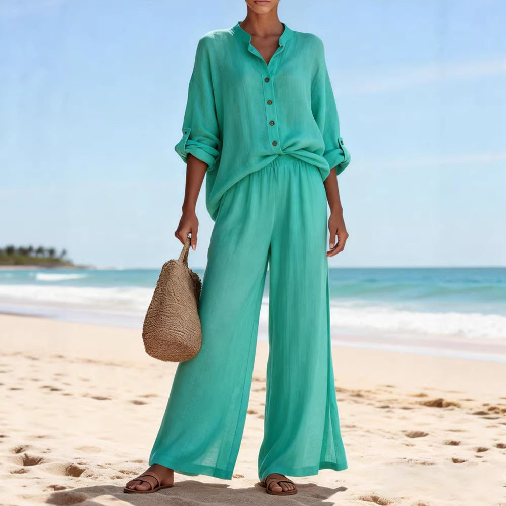 Person wearing a teal outfit on a beach with a clear blue sky.