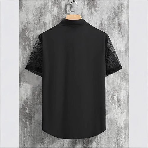 Black shirt with lace sleeves on a hanger against a textured wall.
