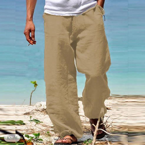 Person wearing beige pants standing on a beach with a clear blue sky.