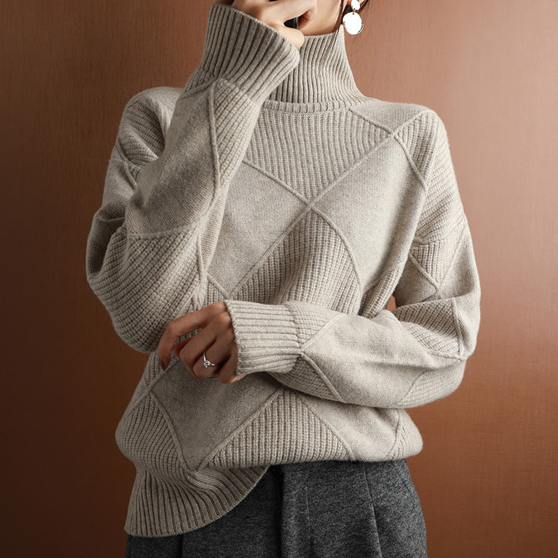 Person wearing a beige turtleneck sweater with geometric pattern against a brown background