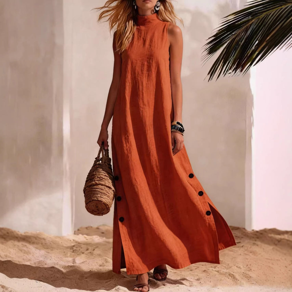 Woman in an orange dress standing on sand with a palm leaf in the background