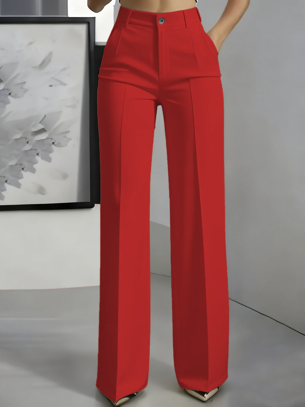 Red pants worn by a person in a minimalistic setting with a framed picture on the wall.
