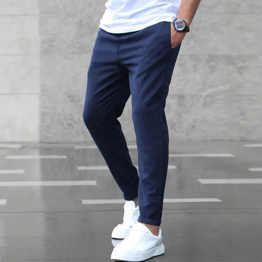 Person wearing navy jogger pants and white sneakers on a gray pavement.
