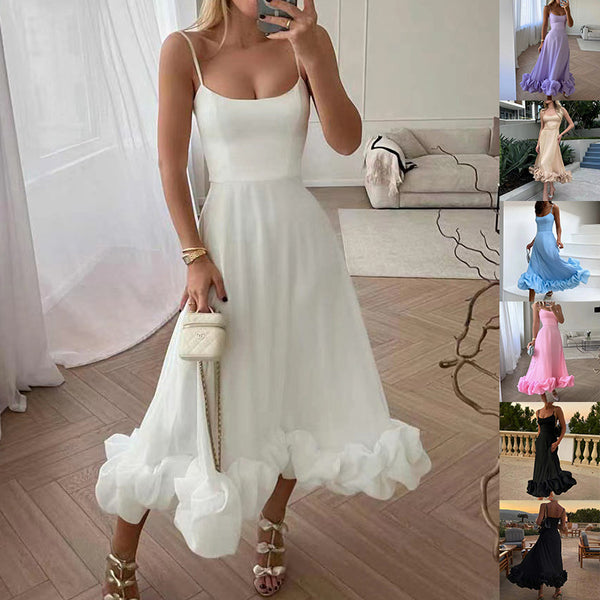 Woman in a white dress taking a selfie in a room with a couch and window.