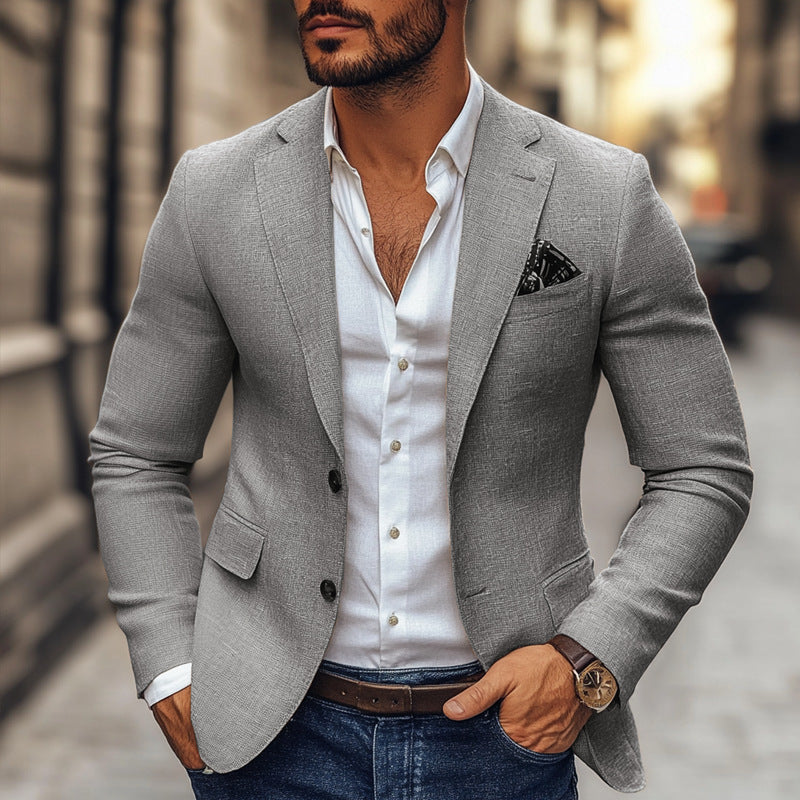 Man wearing a gray blazer over a white shirt with a blurred street background