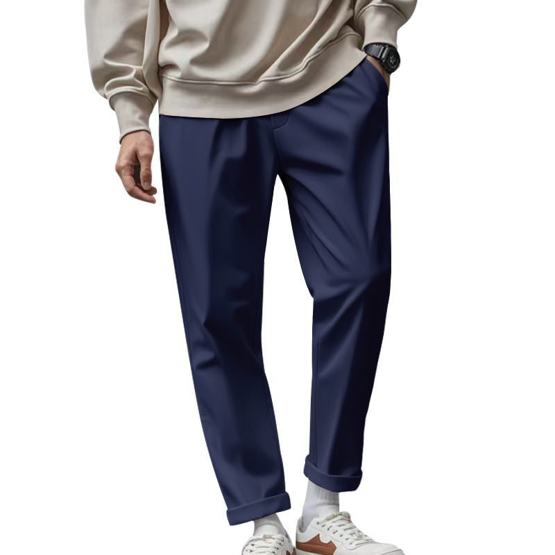 Person wearing navy pants and a beige sweater on a white background