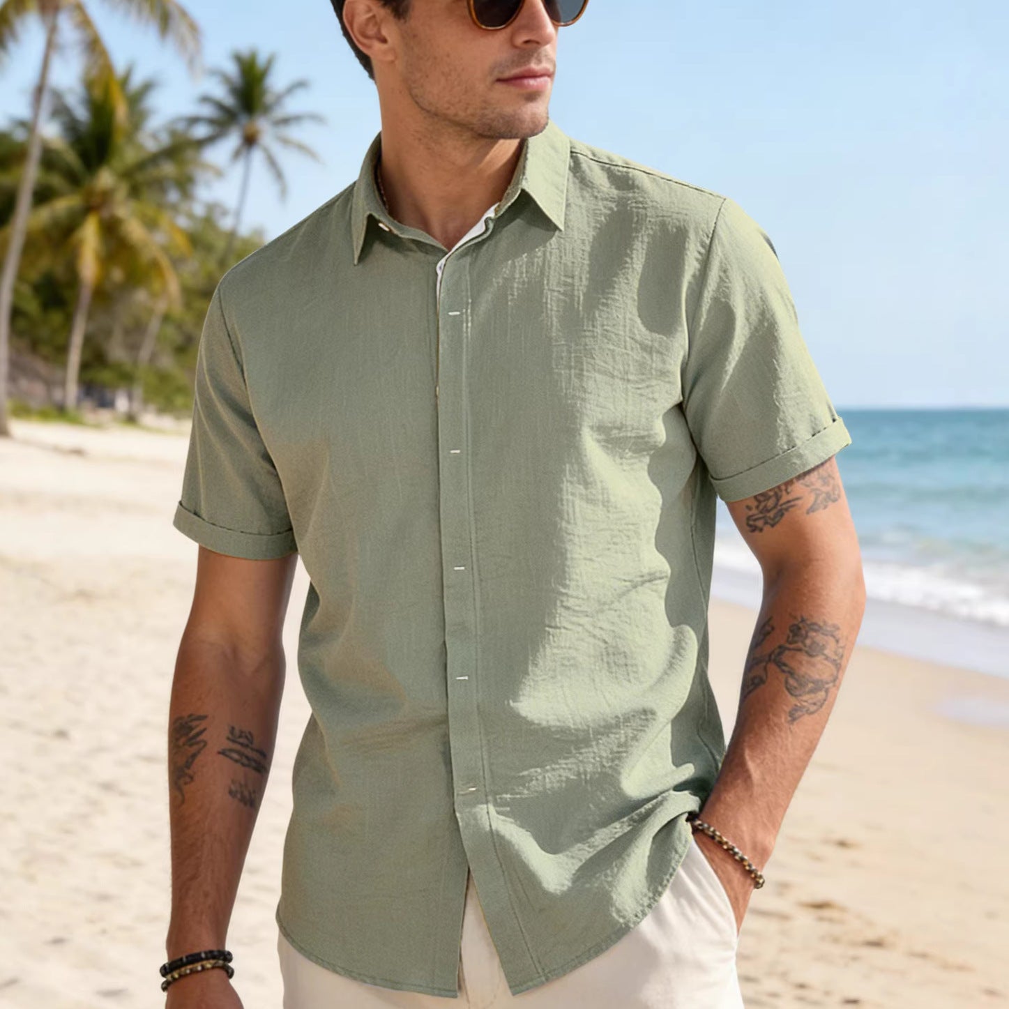 Man wearing a green shirt on a beach with palm trees and ocean in the background
