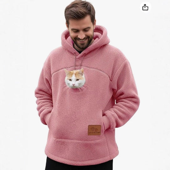 A man wearing a pink sherpa fleece hoodie with a realistic cat face printed on the chest, set against a plain white background.