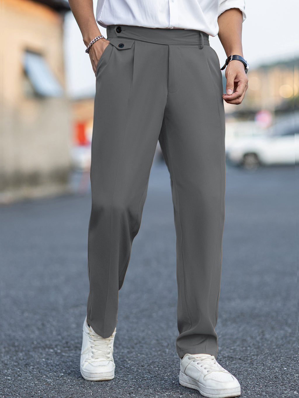 Person wearing gray pants and white sneakers on a blurred street background