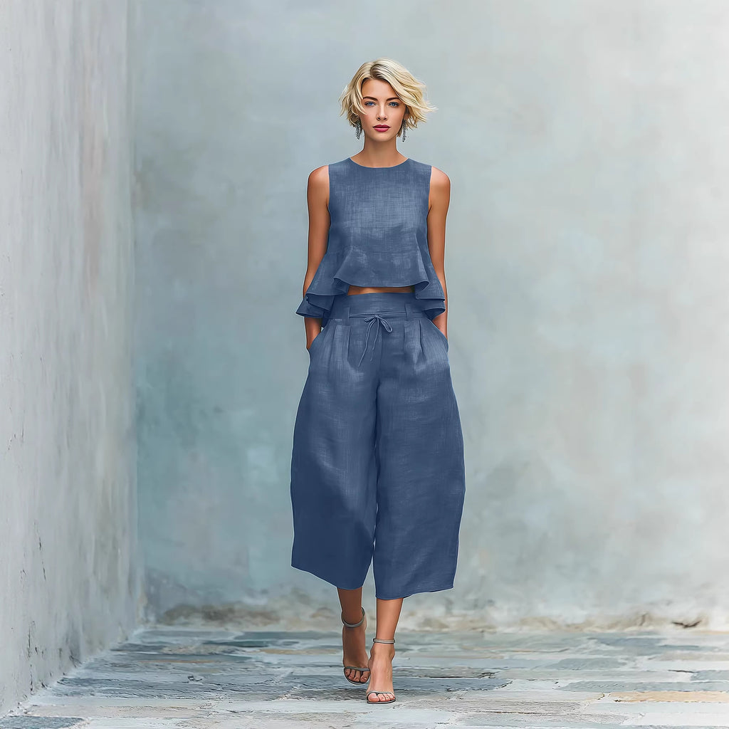 Woman wearing a blue outfit standing against a textured wall.