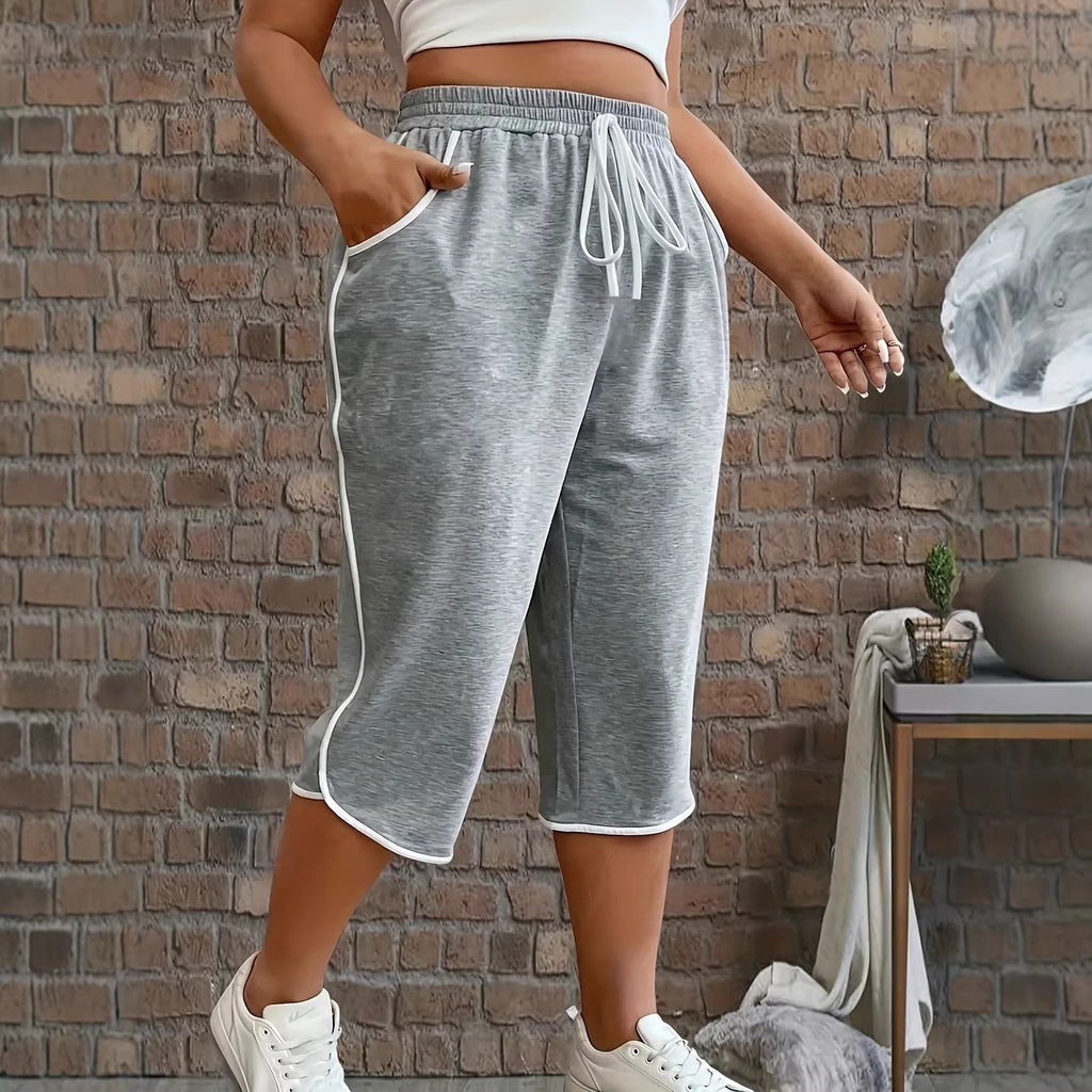 Person wearing gray sweatpants with a white top against a brick wall.