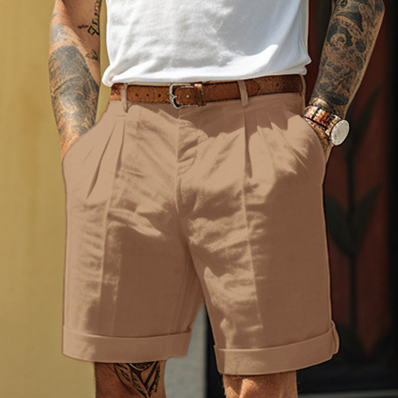 Person wearing beige shorts with a white shirt and brown belt, standing against a blurred background.