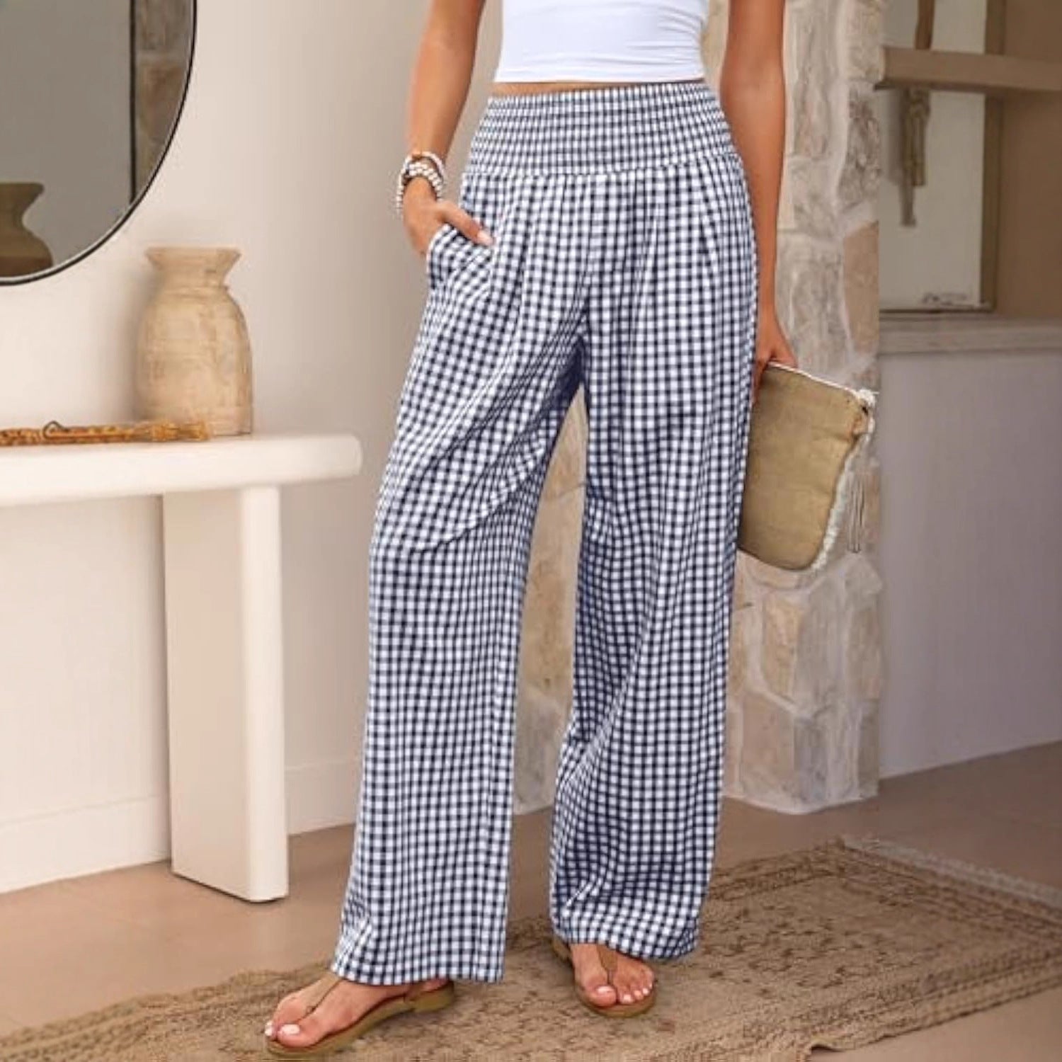 Person wearing blue and white checkered pants standing in a room with a stone wall and table.