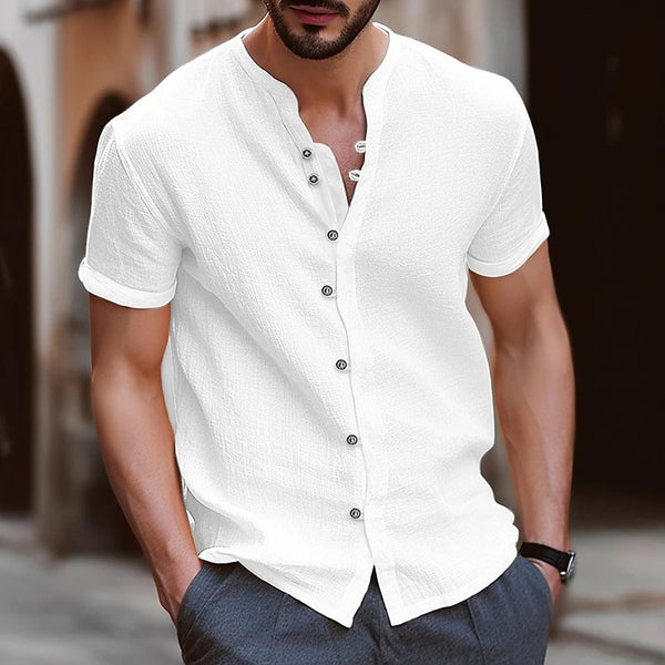 Man wearing a white short-sleeve button-up shirt with a blurred background