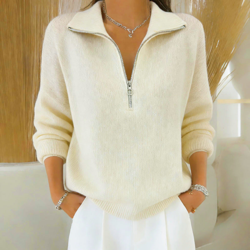 Person wearing a cream-colored zip-up sweater with a blurred background