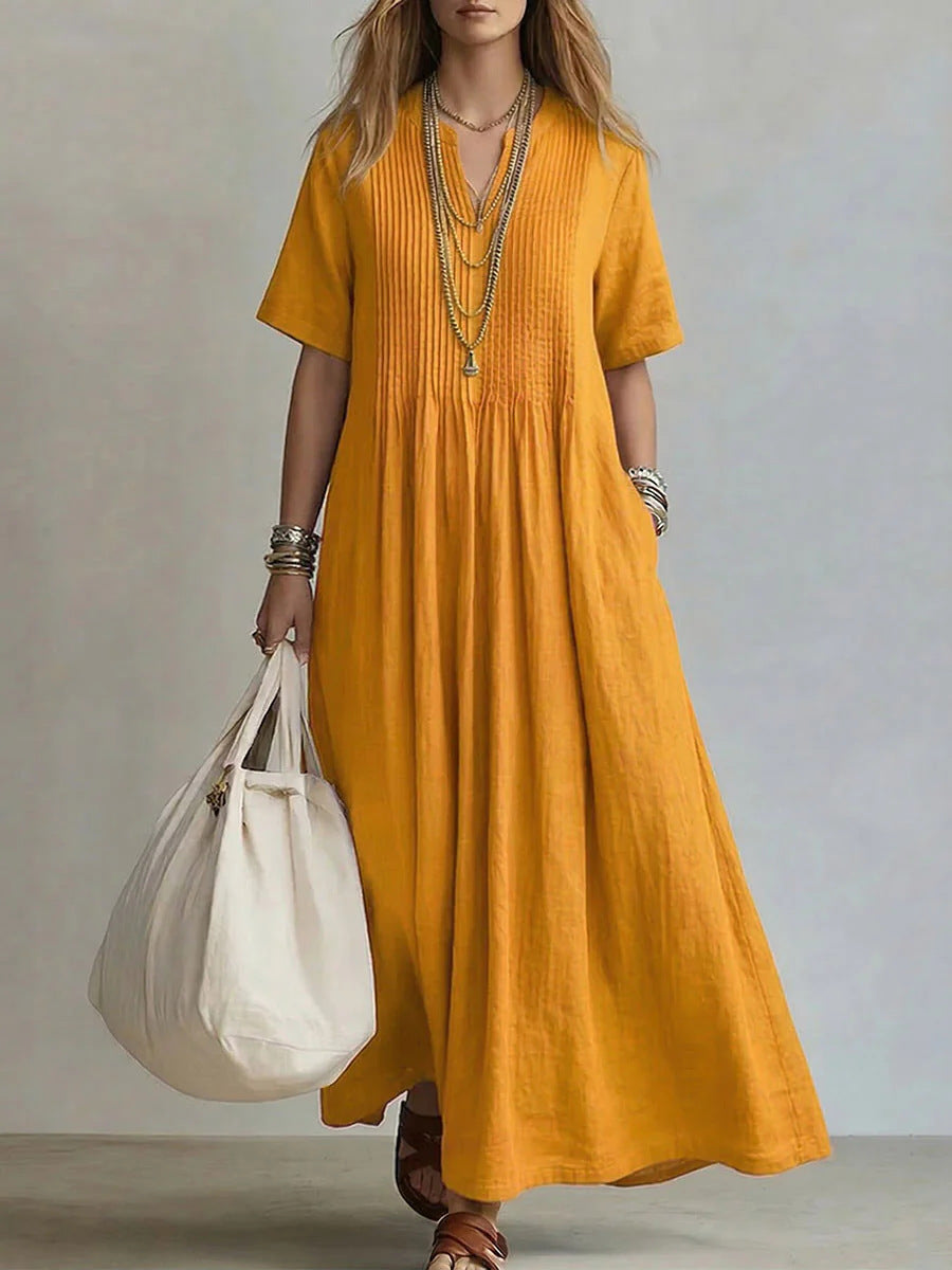 Woman wearing a mustard yellow dress holding a white bag against a neutral background