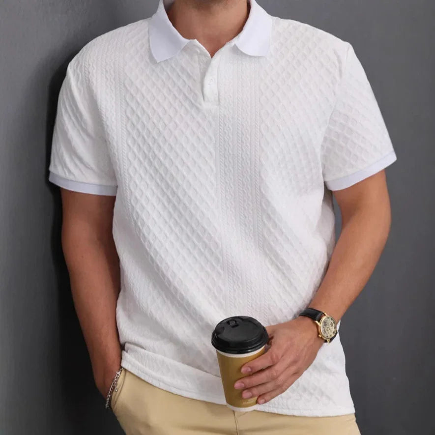 Person wearing a textured white polo shirt holding a coffee cup against a gray background