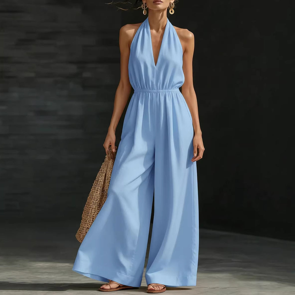 Woman wearing a light blue jumpsuit holding a woven bag against a dark background