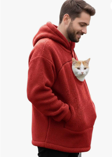 A man wearing a red sherpa fleece hoodie with a cat pocket containing a white and orange cat, shown against a plain white background.