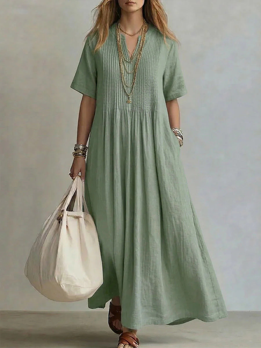 Woman wearing a green dress holding a beige bag against a neutral background