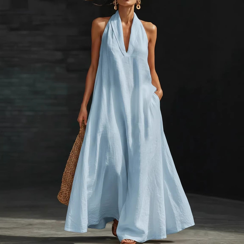 Woman wearing a light blue halter neck dress against a dark background