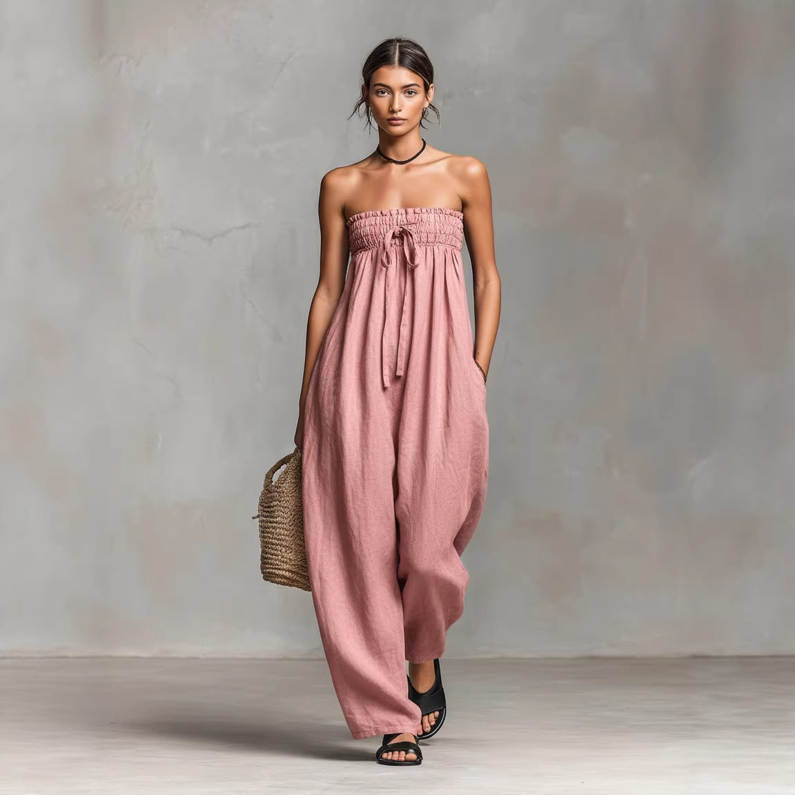 Woman wearing a pink strapless jumpsuit against a neutral background
