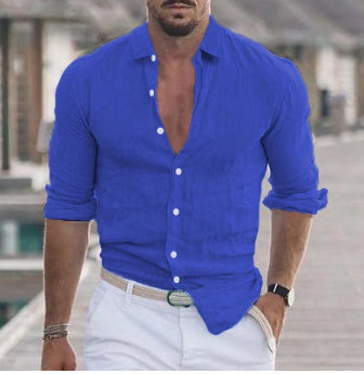 Man wearing a blue button-up shirt and white pants outdoors.