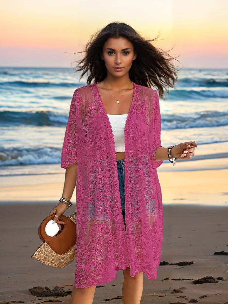 Woman in a pink lace cover-up on a beach at sunset