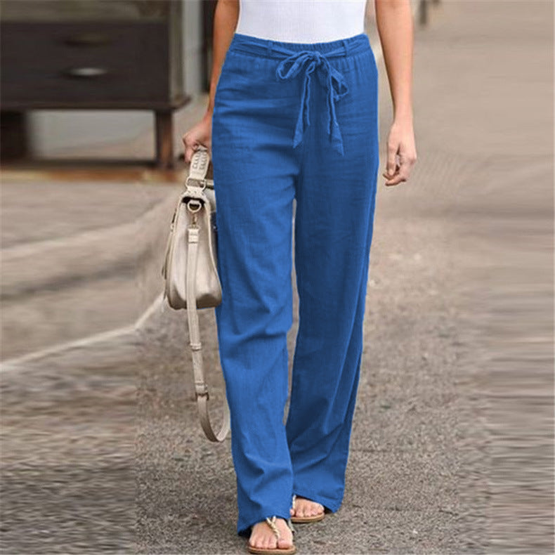Person wearing blue pants holding a beige handbag on a blurred background
