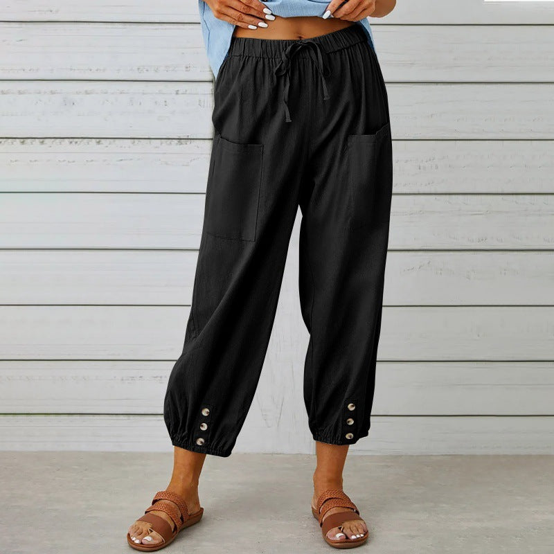 Black wide-leg pants with button details worn by a person against a wooden background