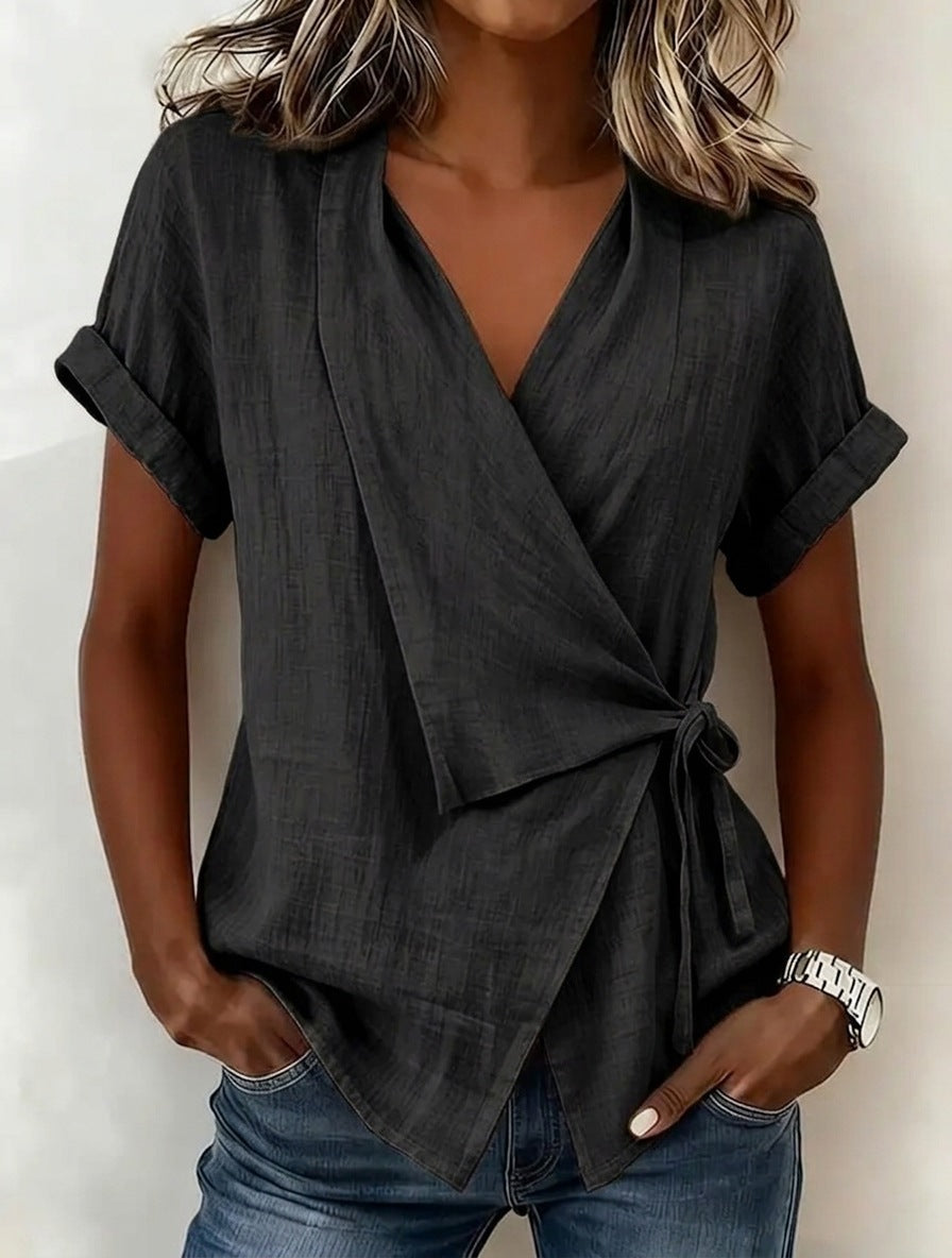Woman wearing a black wrap top and blue jeans against a white background