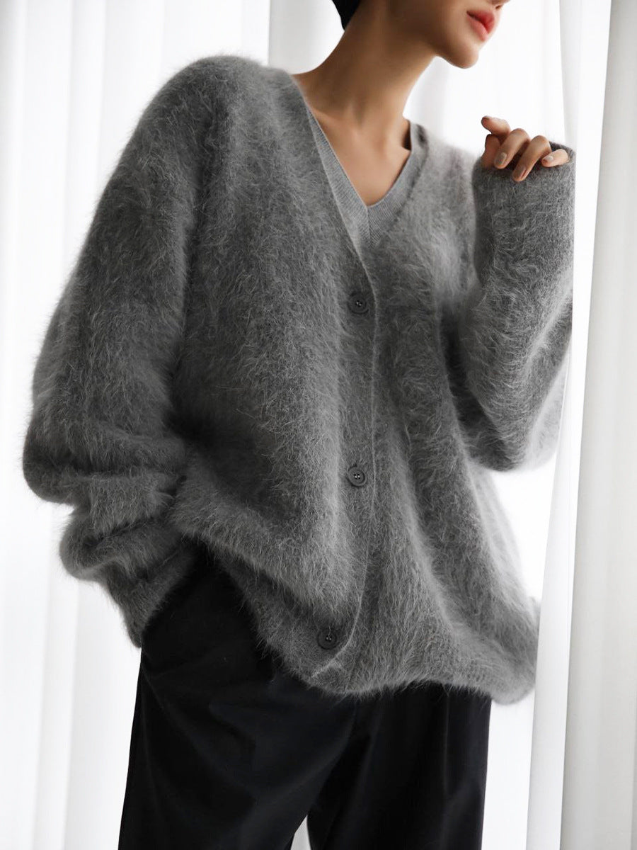 Person wearing a gray cardigan in a minimalistic setting