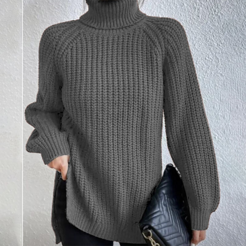 Person wearing a gray knitted sweater holding a black handbag against a light gray background