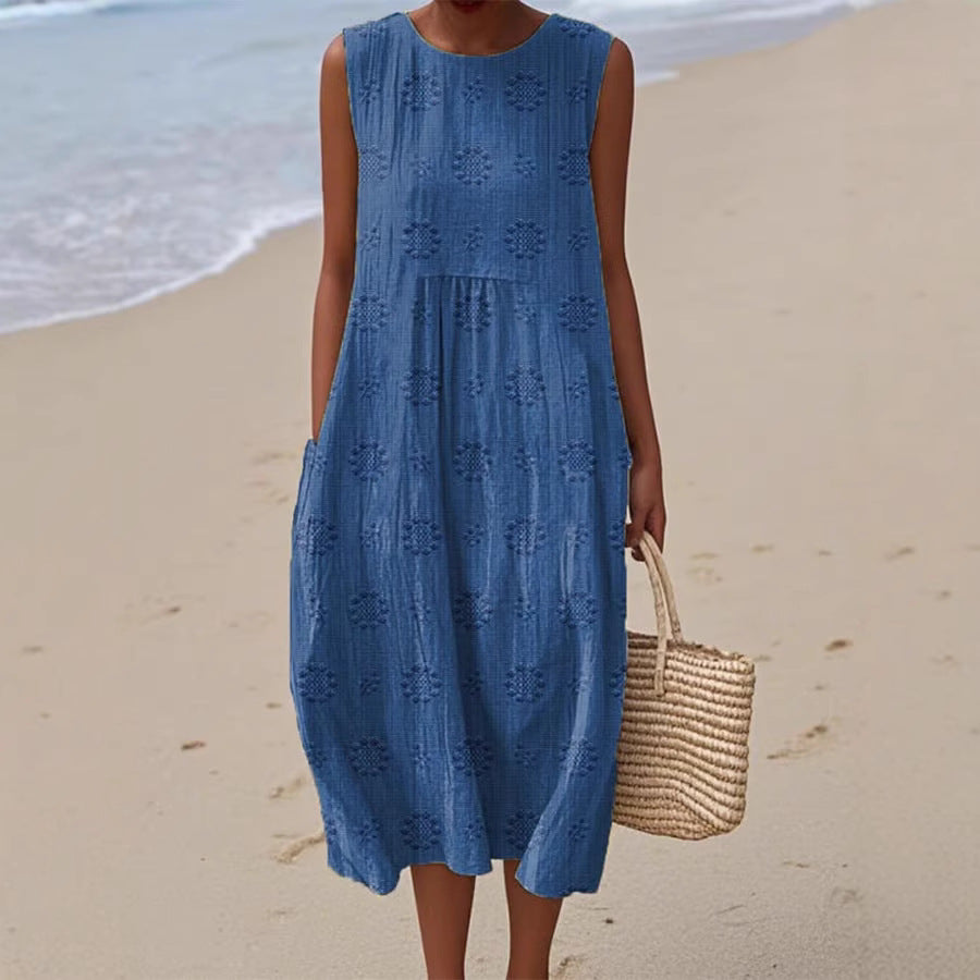 Woman in a blue dress holding a straw bag on a beach