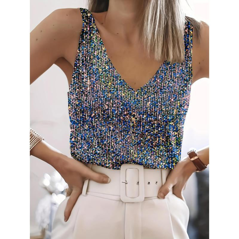 A woman wearing a sleeveless V-neck sequin top with iridescent blue, gold, and silver reflective sequins, paired with a white belt and white trousers.