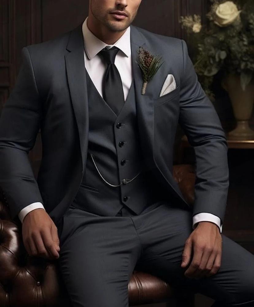 Man wearing a gray suit with a white shirt and tie, sitting on a brown leather chair.