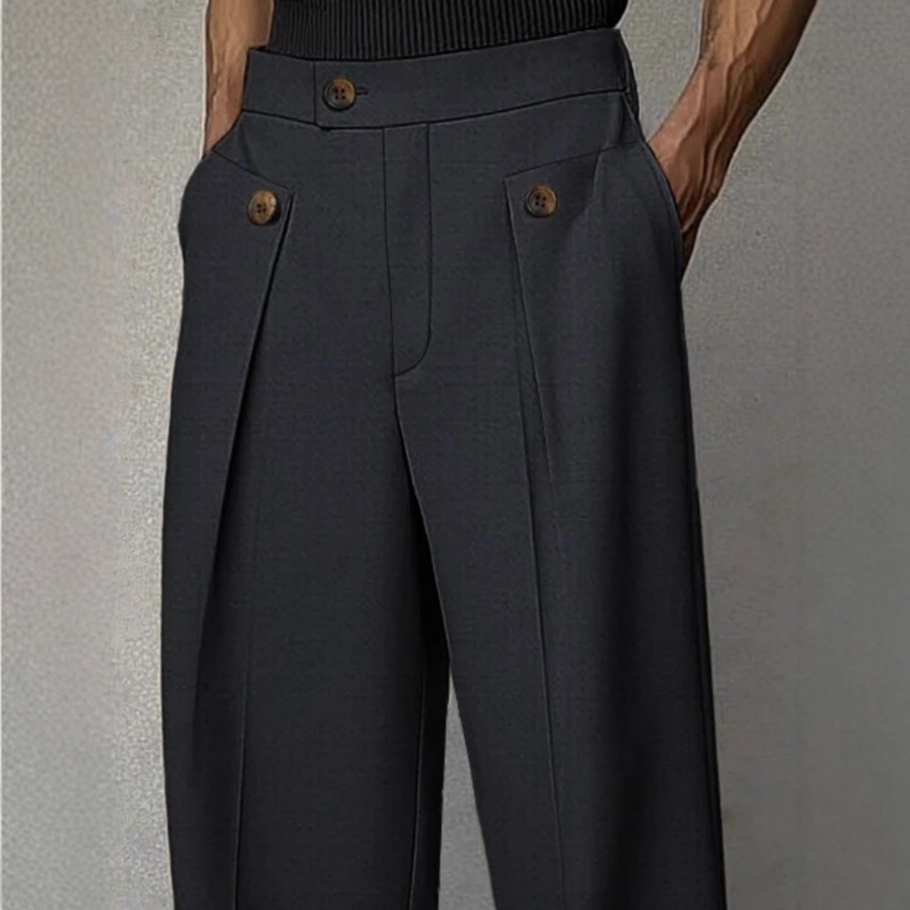 Dark gray pleated pants with button details on a neutral background