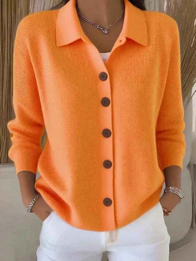 Orange cardigan with brown buttons worn by a person, against a neutral background