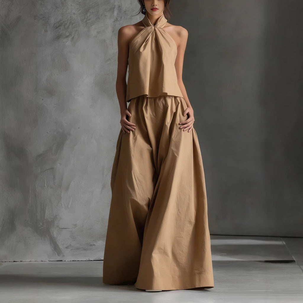 Woman wearing a beige halter top and wide-leg pants against a gray background