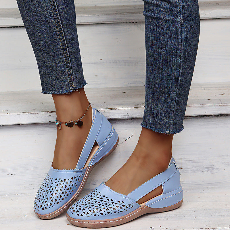Light blue sandals worn with rolled-up jeans on a wooden floor.