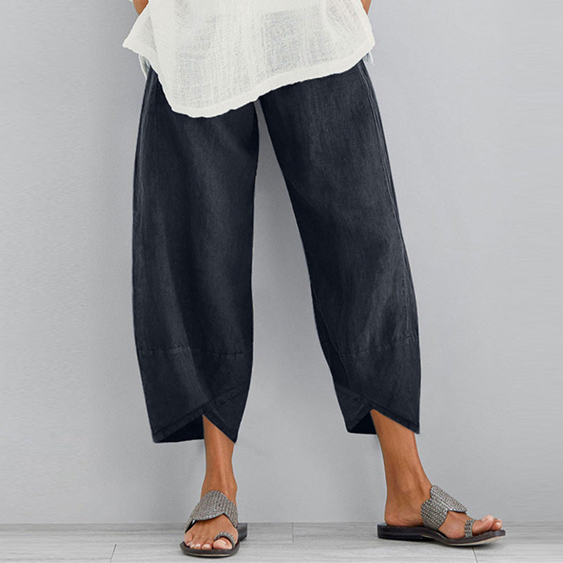 Person wearing black wide-leg pants and a white top on a gray background