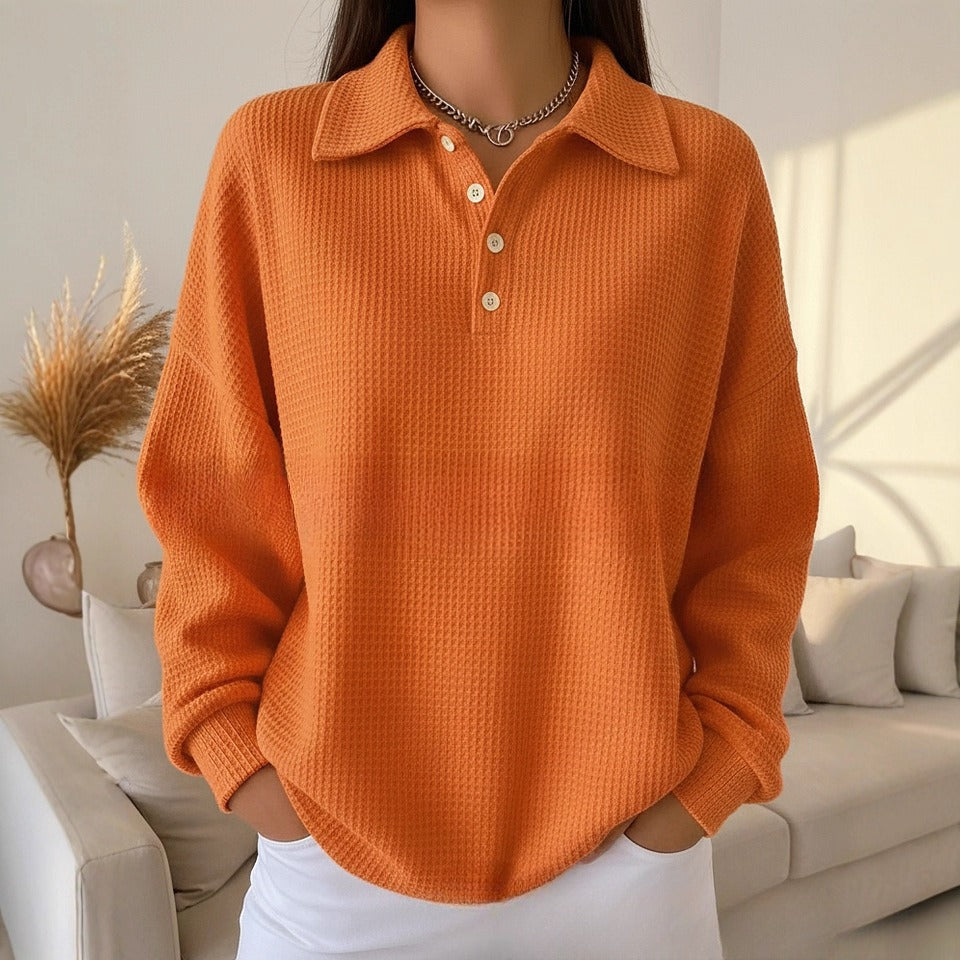 Person wearing an orange textured sweater in a living room setting