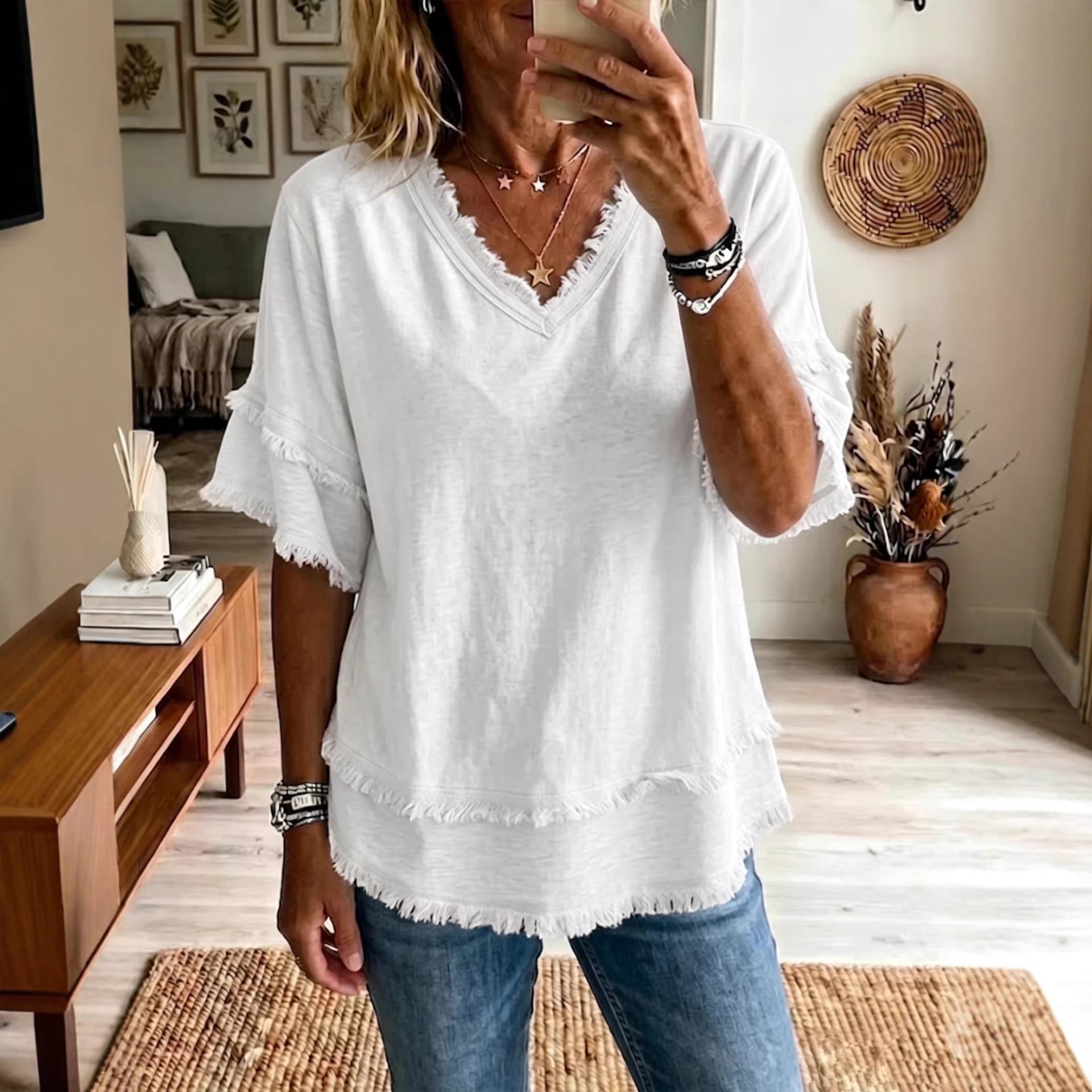 Person wearing a white blouse with ruffled edges in a home setting.