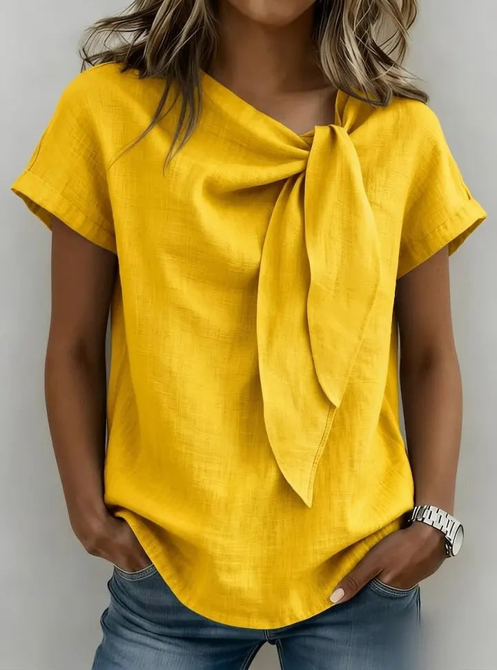 Yellow top with a bow detail worn by a person on a plain background