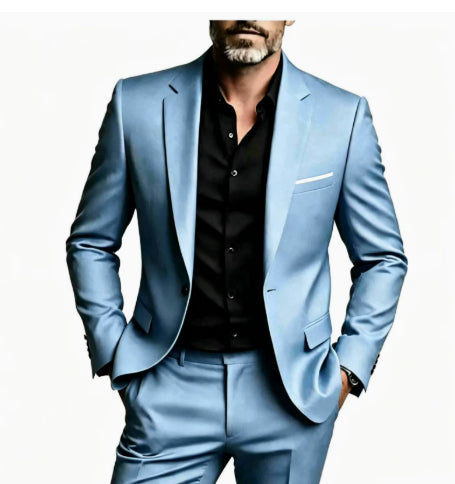 A man wearing a light blue suit with a black button-down shirt, shown from the waist up against a plain white background.
