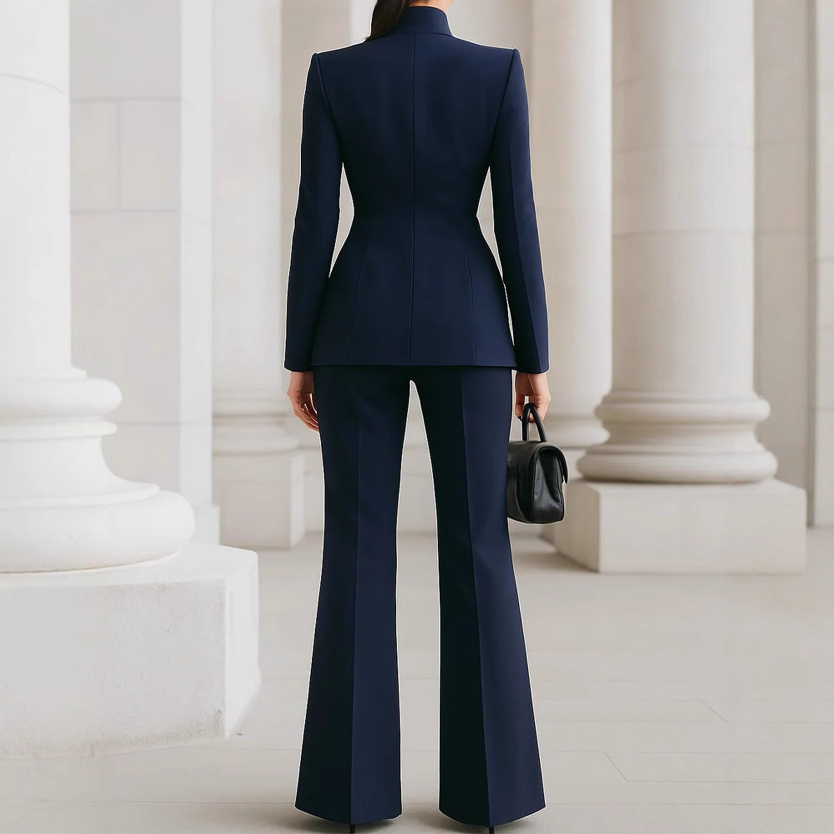 Person wearing a navy blue suit standing in front of classical columns.